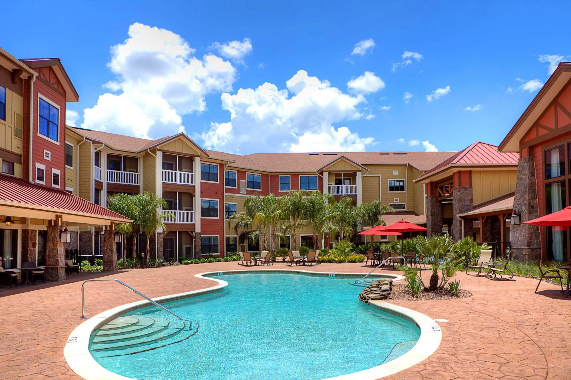 A pool and pool deck surrounded by senior living apartments on a sunny day in the Villages in Florida