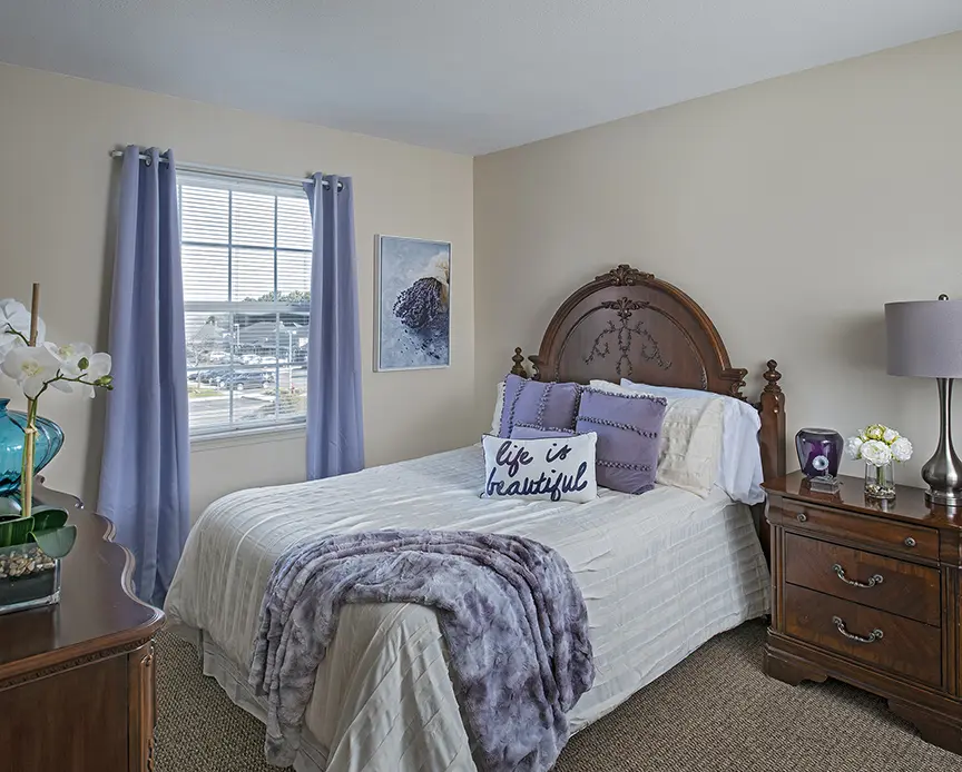 Bedroom at West Bloomfield retirement home with purple curtains and pillows
