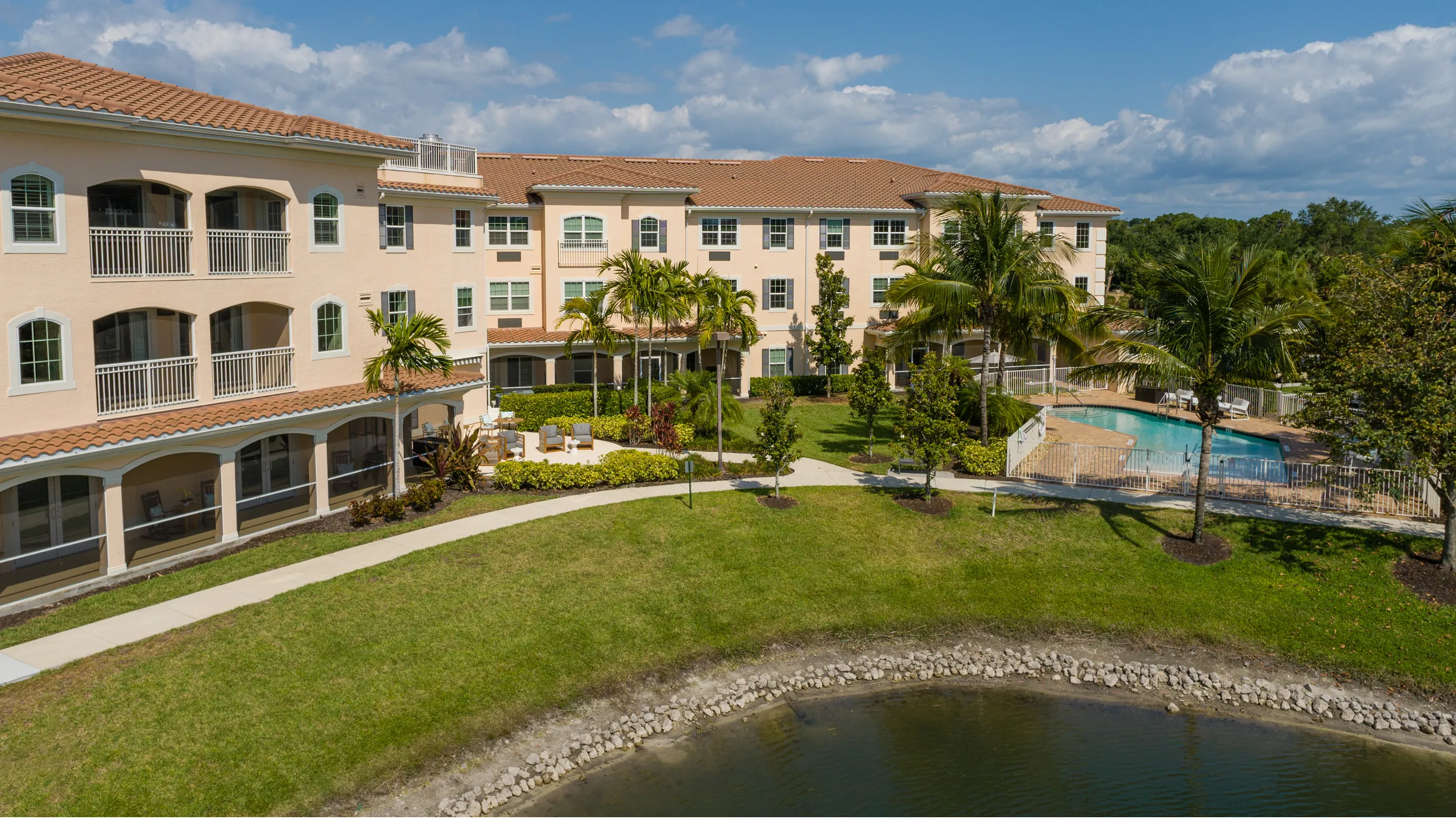 rear exterior of senior living community in bonita springs with pool and lake shore