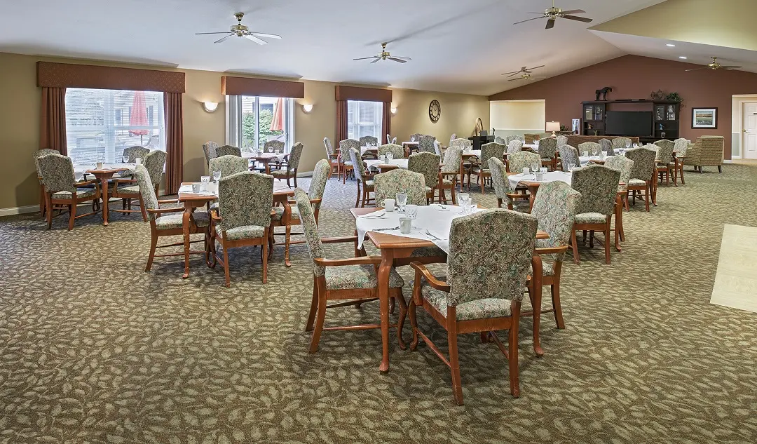 Carpeted dining hall of American House Charlevoix, a senior living community in Charlevoix, Michigan