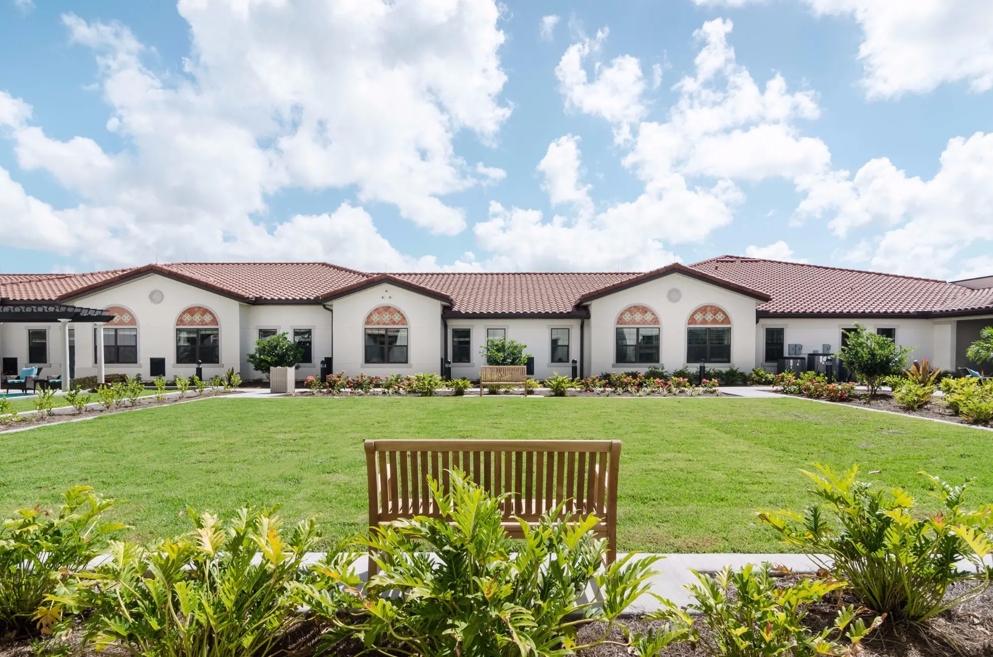 Exterior shot / courtyard of American House Coconut Point, a senior living community in Estero, FL