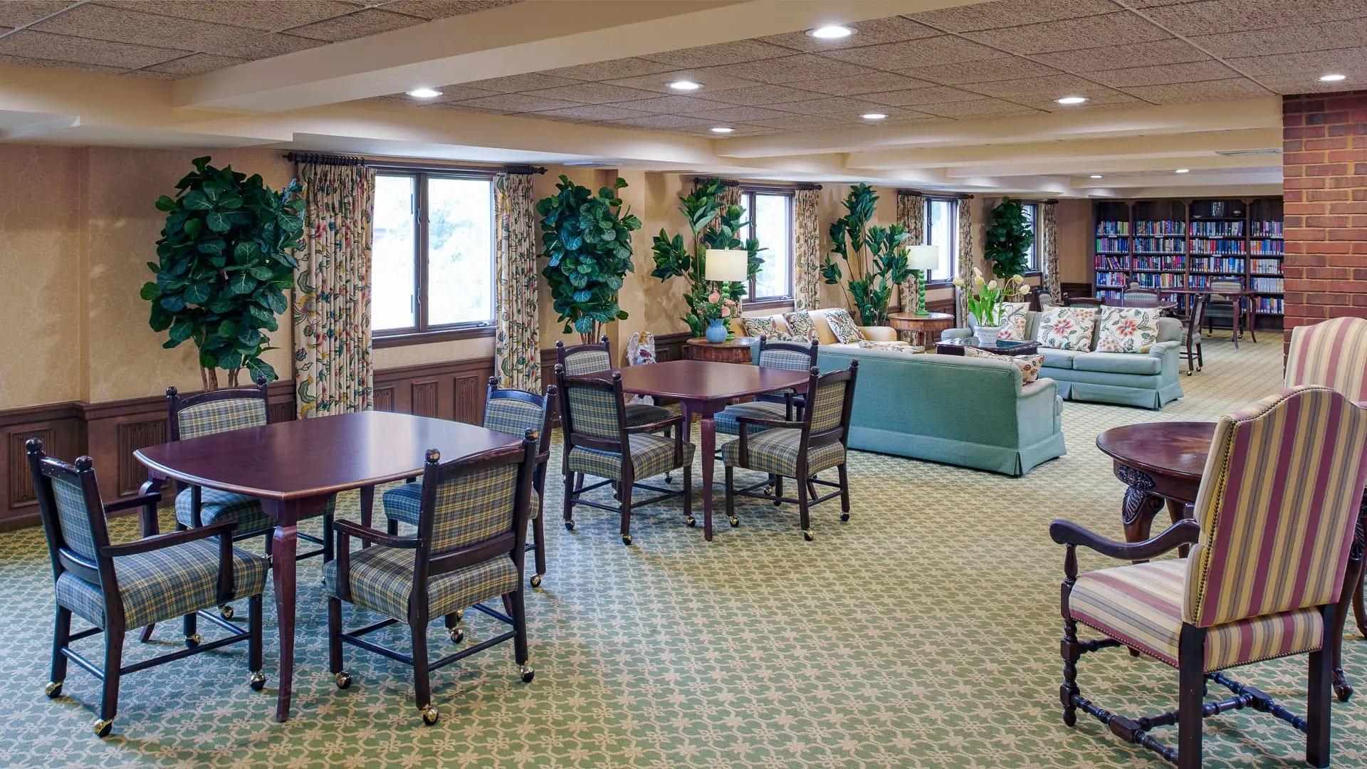 Carpeted common area with library at American House East I, a senior living community in Roseville, Michigan
