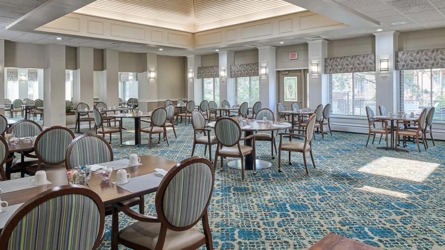 Large carpeted dining hall at American House East II, a senior living community in Roseville, Michigan