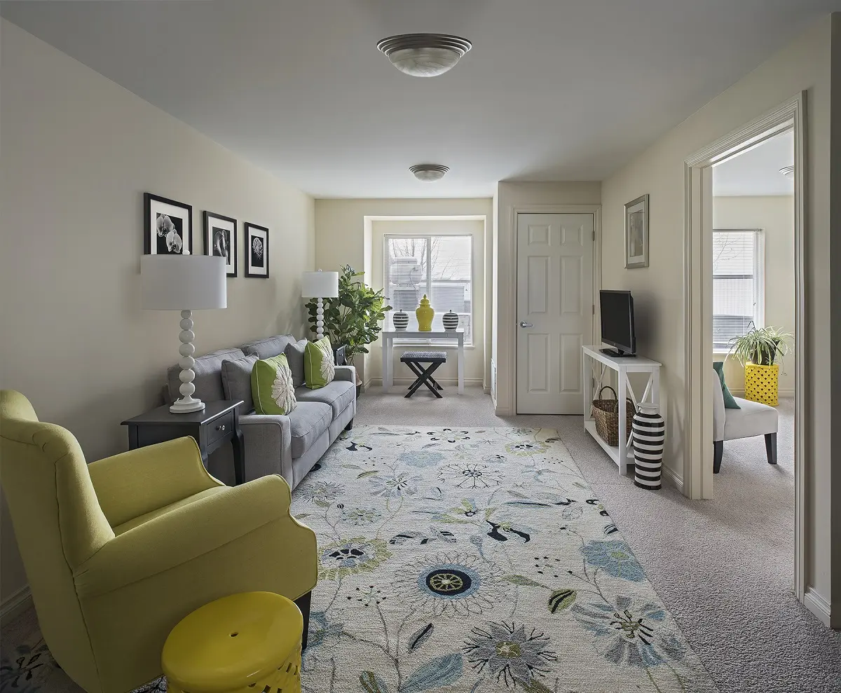 Living room with yellow and gray furniture at senior living community in North Sterling Heights, MI