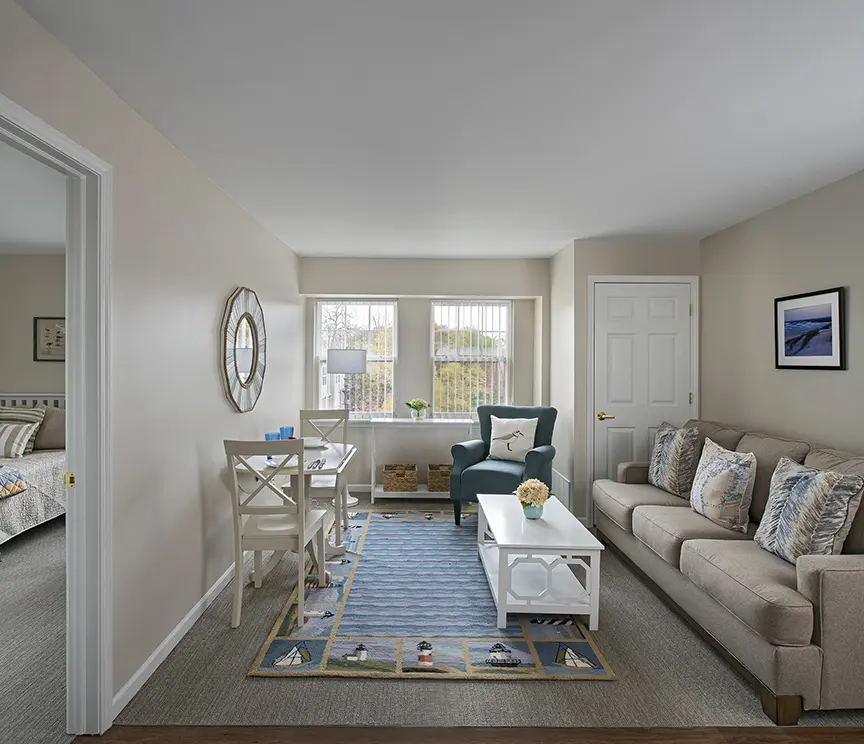 A well furnished living area, a rug in the middle with lighthouses in a retirement home apartment in Rochester Hills, MI