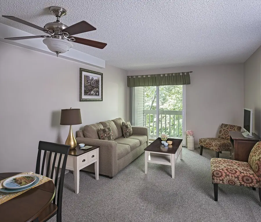 Living room with a balcony in an independent living apartment at American House in Westland, MI.