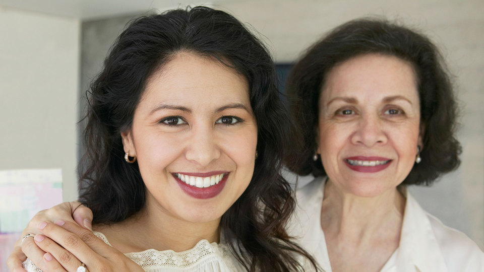 A middle-aged woman and her older mother facing the camera and smiling