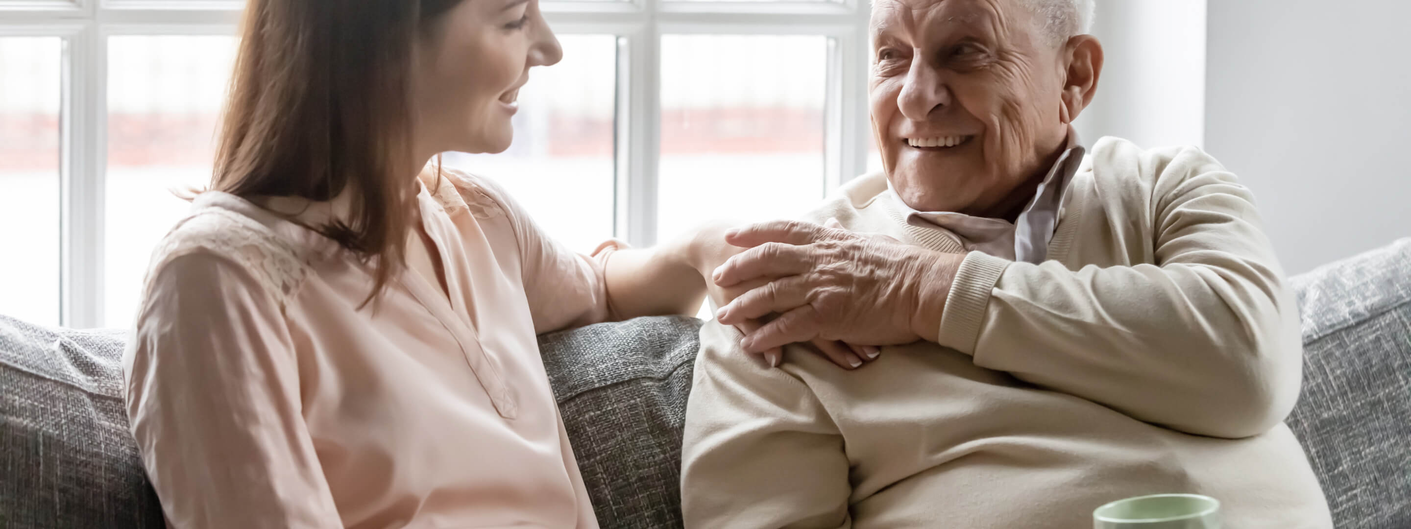 A woman and her senior citizen father having a conversation on a couch